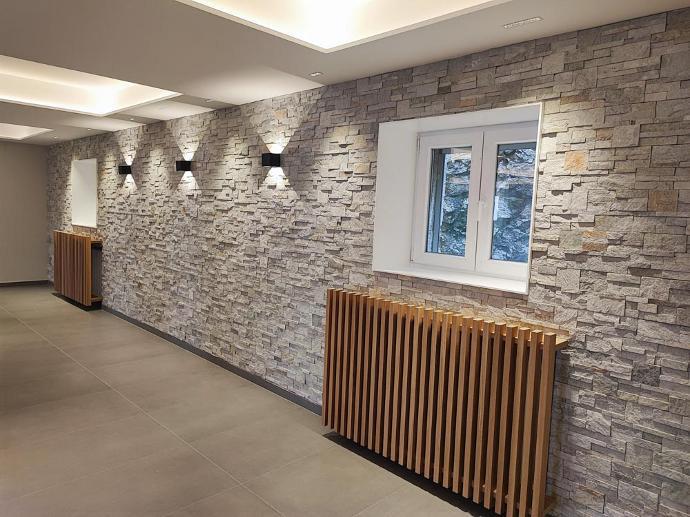 Muro de piedra con ventanas y radiadores con apariencia de madera